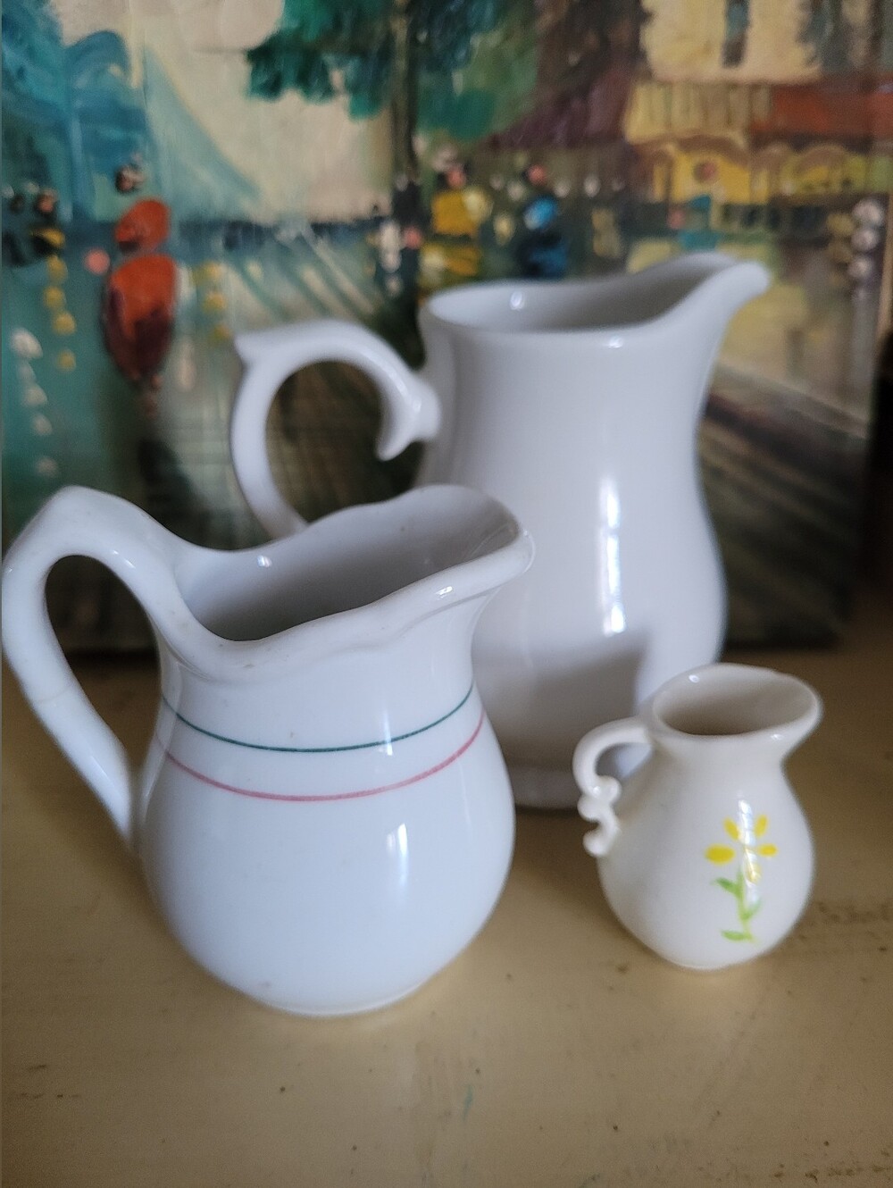 White Ceramic Pitcher Trio with Delicate Banding and Floral Accent